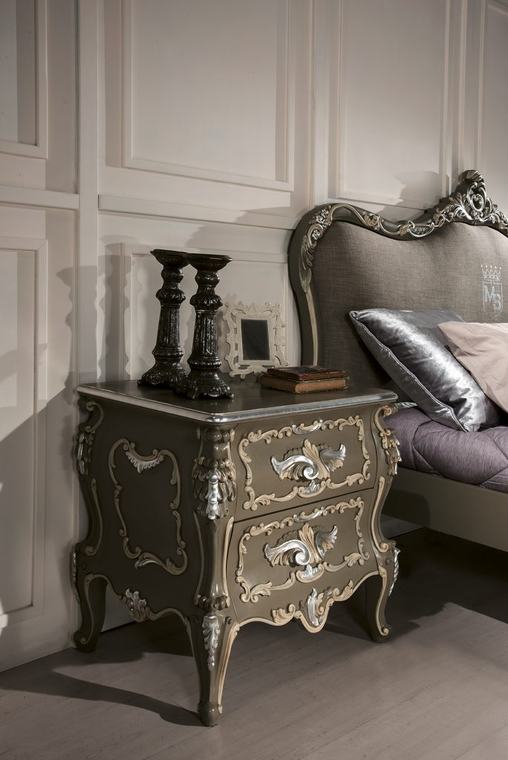 Comodino laccato con decori argentati dipinti a mano accanto a un letto
